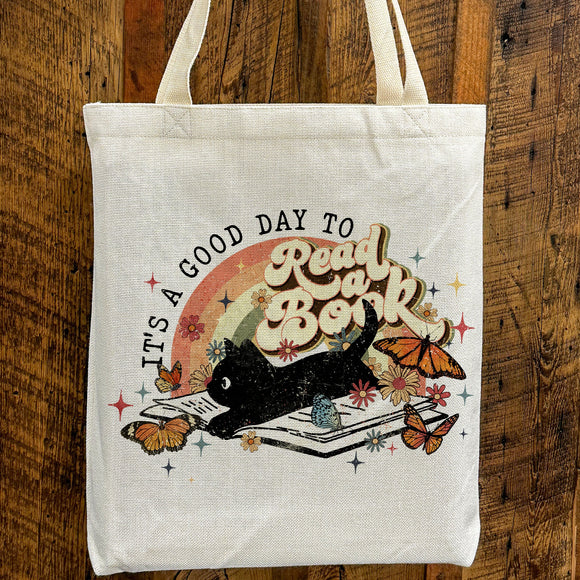 a white tote bag with a picture of a cat reading a book