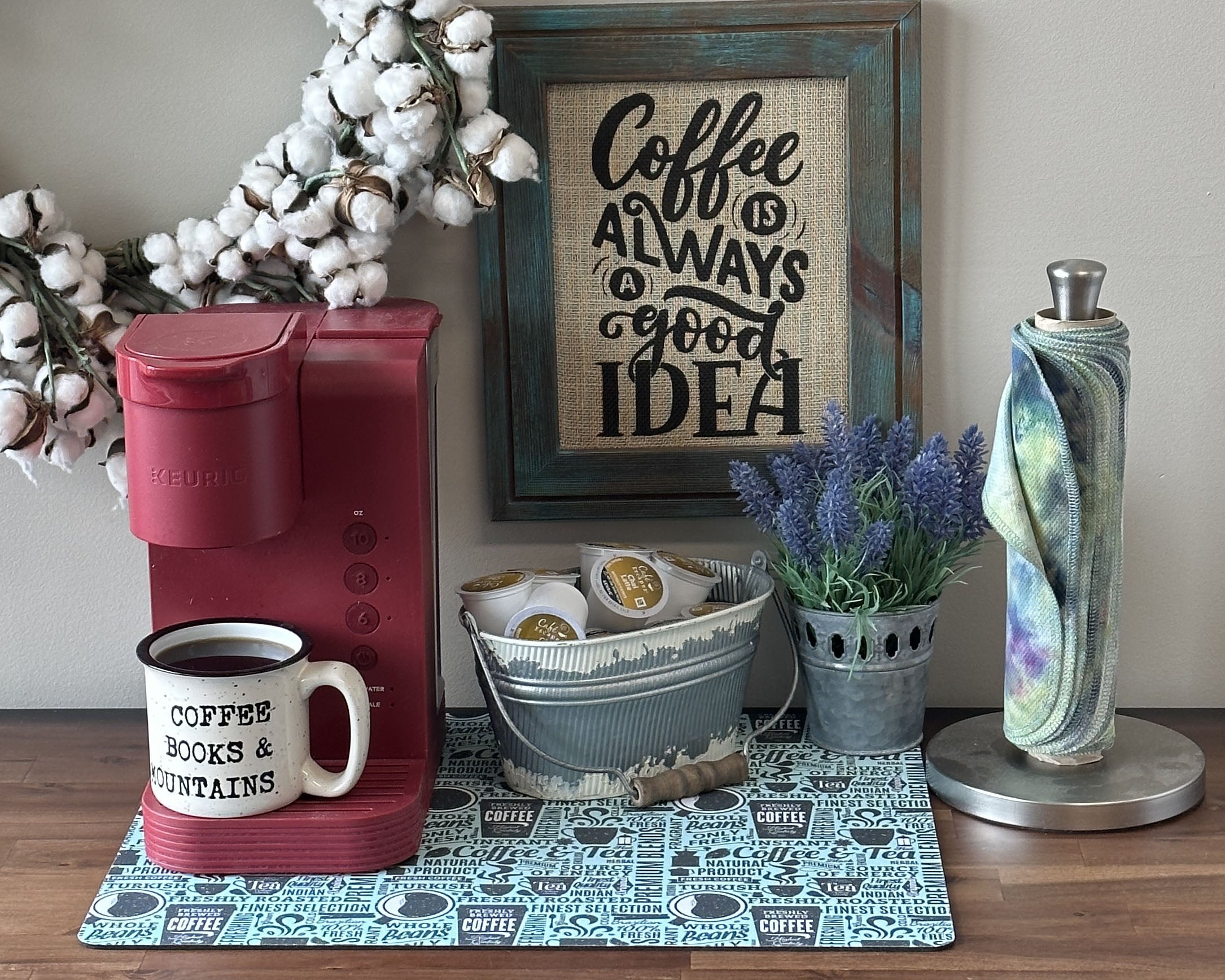 red coffee maker on a blue counter mat with a cup of coffee