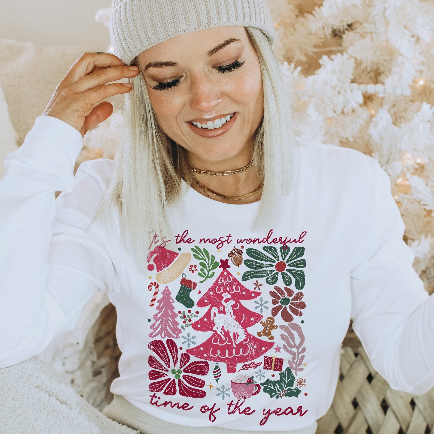 Woman wearing a white sweater with Wyoming Christmas-themed design boho style, sitting in a cozy indoor setting