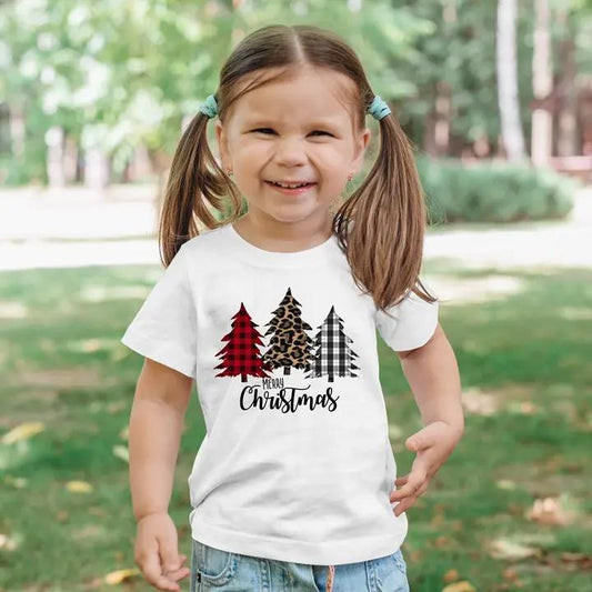 a little girl wearing a white shirt with christmas trees on it