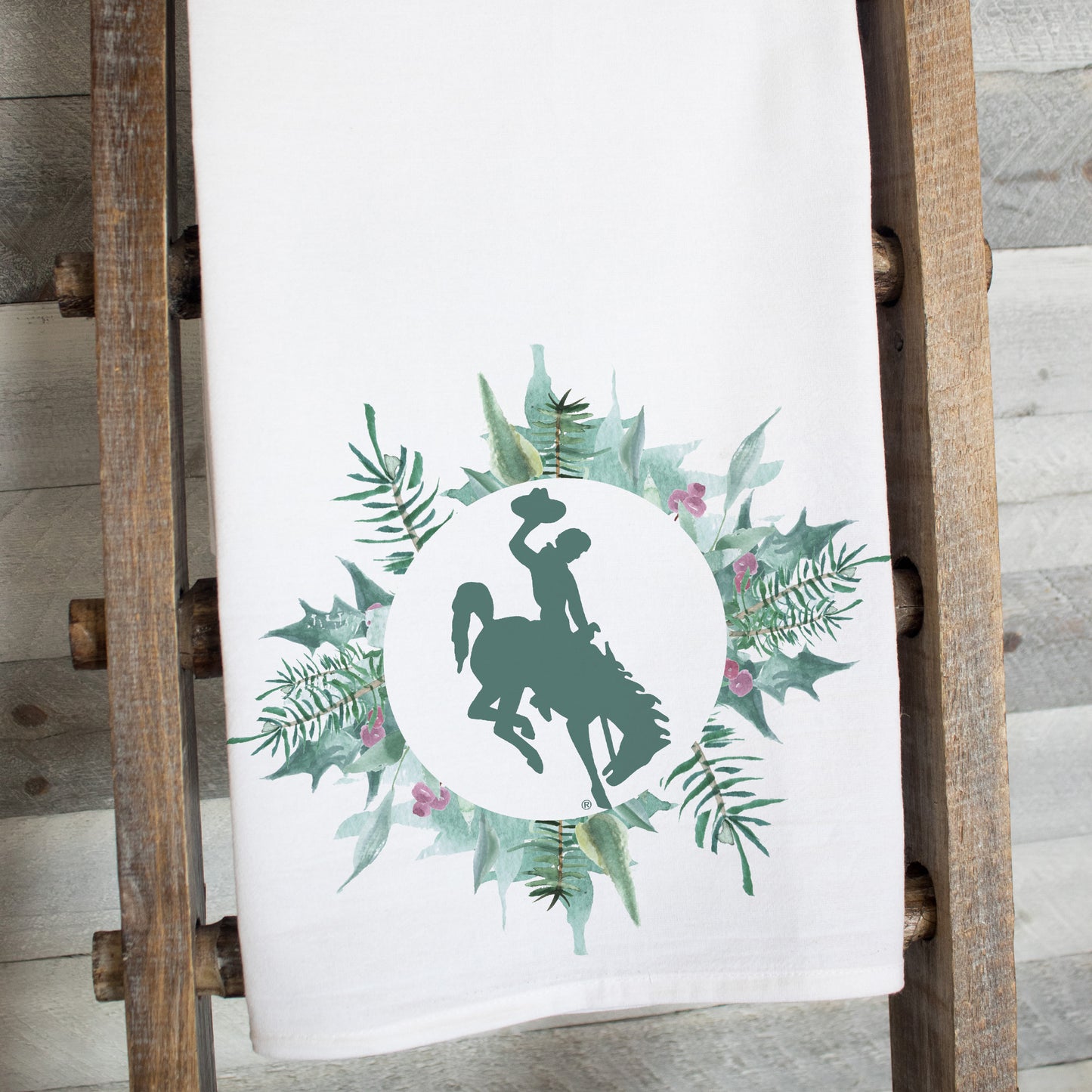 Sugar Plum Bucking Horse tea towel featuring Wyoming bucking horse silhouette framed by watercolor greenery and pink florals
