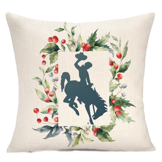 Officially licensed Winter Holly Bucking Horse™ pillow with Wyoming bucking horse silhouette framed by watercolor holly and berries, on natural linen or white velvet cover.