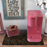 a pink coffee maker sitting on top of a wooden table